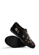 Display of black cartoon frog tattoo slip-ons stacked to show sole and side frog illustrations