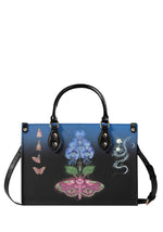 Gothic handbag with pink death moth, blue mystical flowers, and serpent motif on black-to-blue gradient background