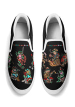 Black slip-ons with white sole and trim, decorated with funky frog tattoo graphics and colorful typography