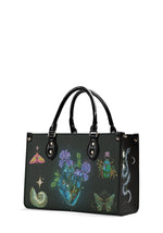 Side view of gothic handbag featuring iridescent beetle, floral heart, moth, and swirling constellation serpent