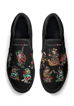 Black slip-on shoes with retro tattoo-style frog illustrations and rainbow "Tattoos are Stupid" text on the top